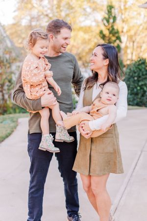 Young couple with two small children share loving moment on outdoor walkway.