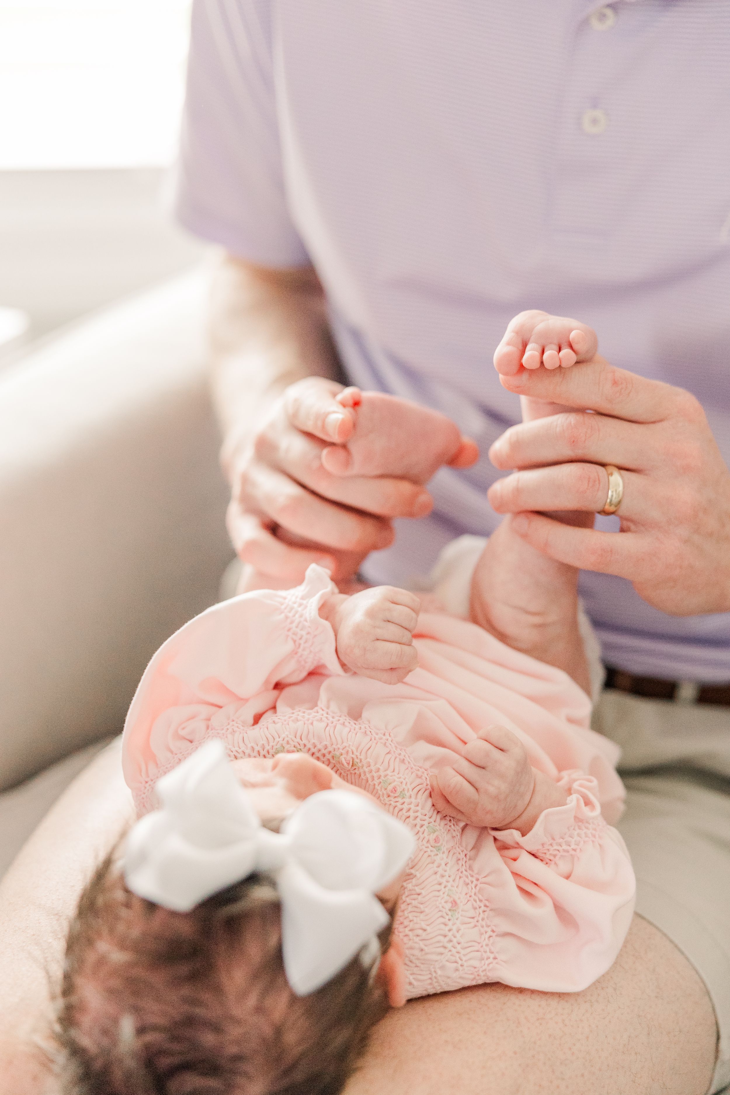 Close-up of parent's hands holding newborn baby's tiny feet during intimate family moment.