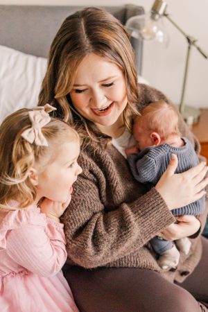 Family moment with baby and toddler in pink dress sharing joyful expressions.