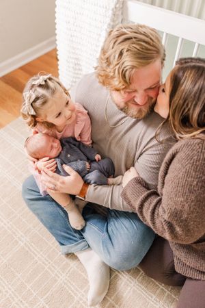 Intimate family portrait with toddler and baby sitting together.