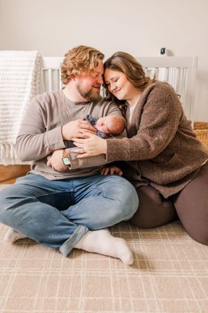 Tender family moment with baby between parents on floor.