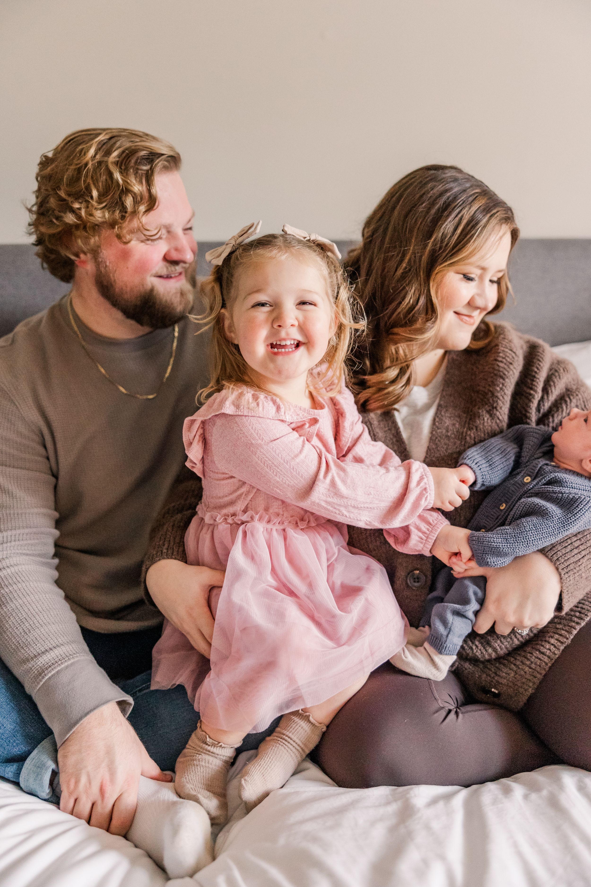 Happy family moment with parents and children sharing smiles on cozy bed.