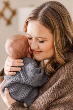 Sweet nurturing moment with baby in gray sweater snuggling close.