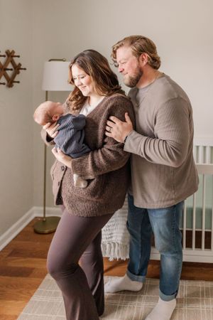 Intimate family portrait in nursery with baby in gray sweater.