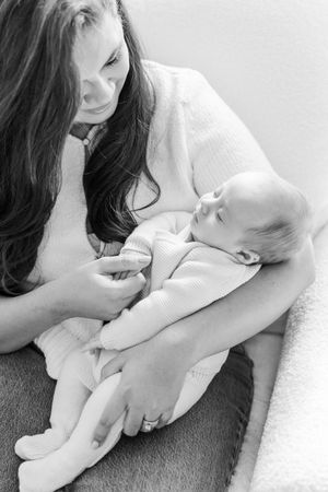 Black and white portrait of parent cradling sleeping newborn in soft lighting.