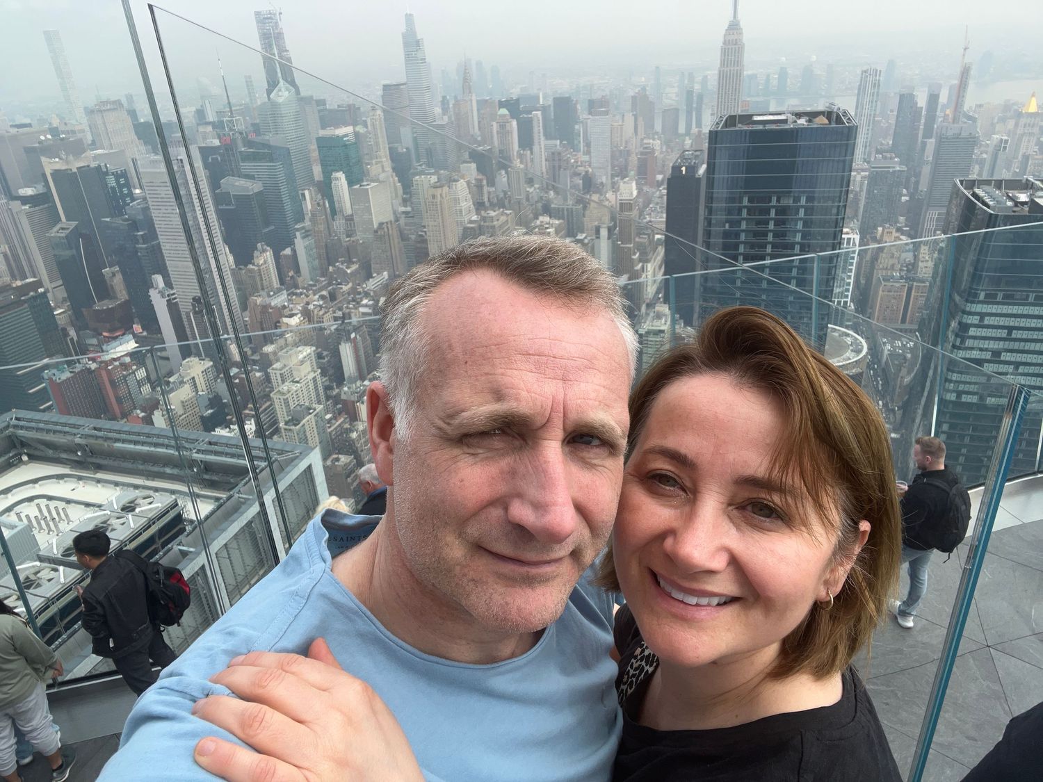 Couple takes selfie from observation deck overlooking New York City skyline.