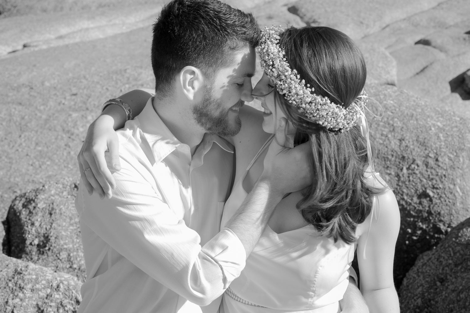 Intimate black and white portrait of loving embrace on rocky beach.