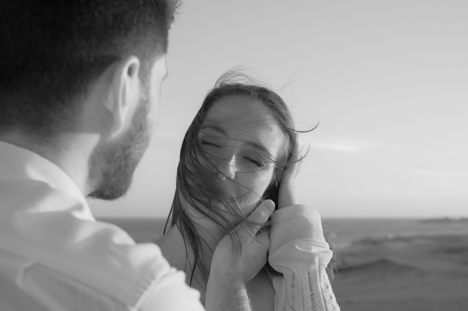 A black and white portrait of two people in an intimate moment outdoors.