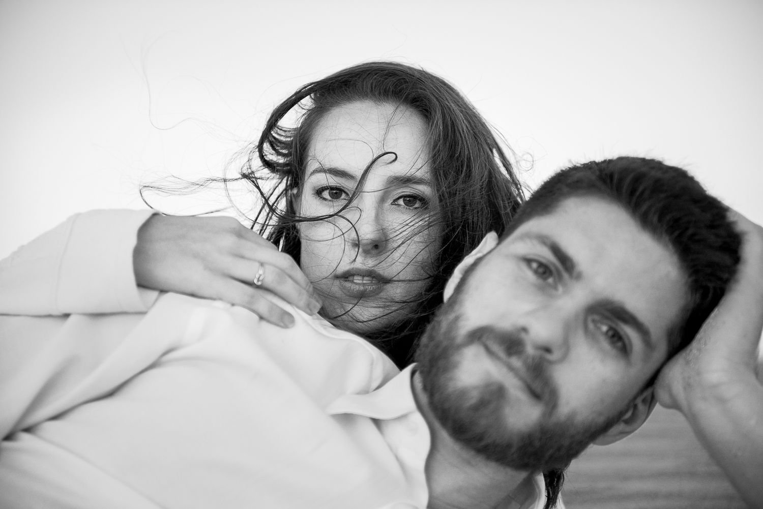 A casual black and white close-up portrait of a couple lying down.
