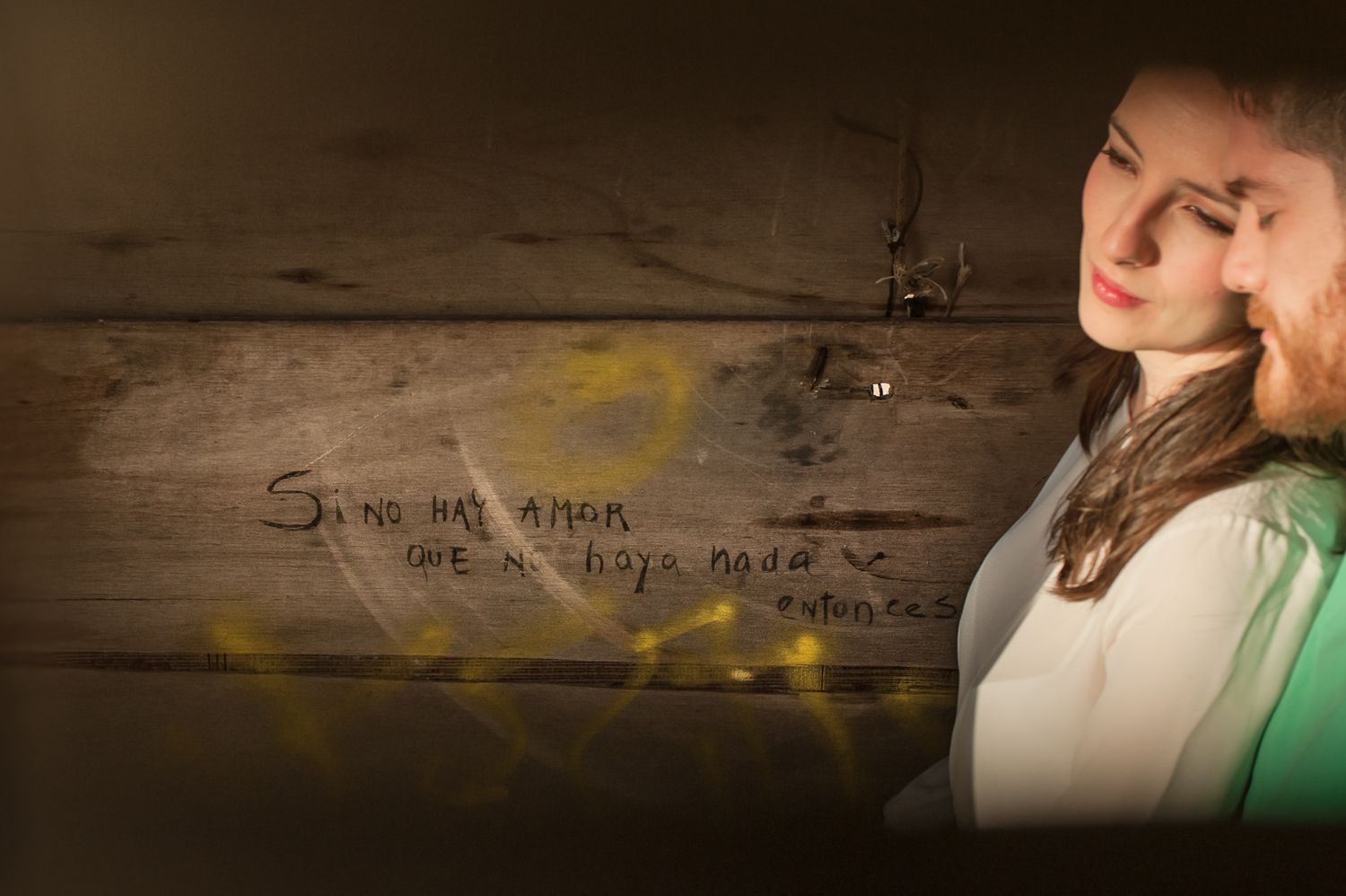 A dramatic portrait against a wooden wall with soft string lights in the background.