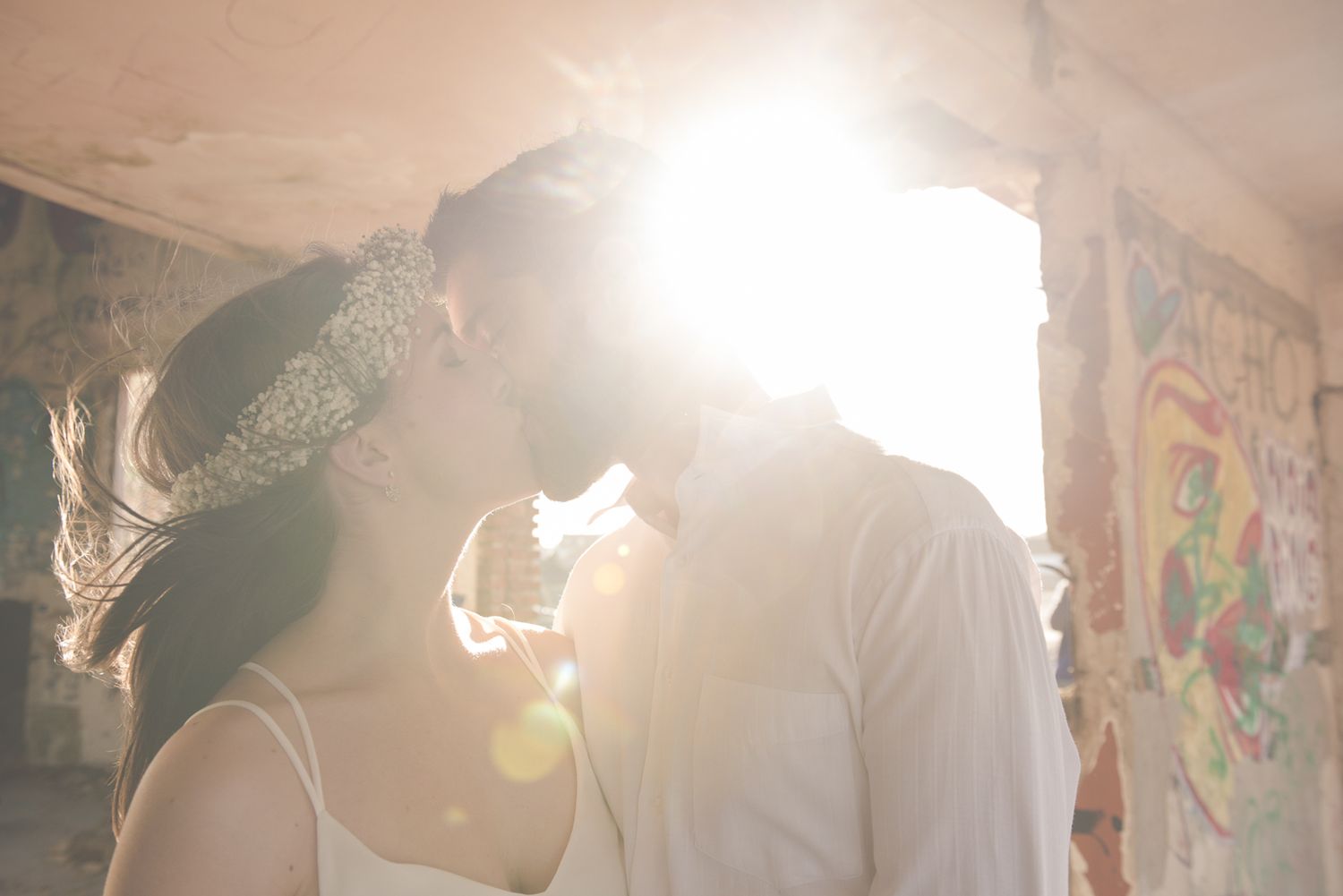 Sunlit portrait with lens flare creating dreamy atmosphere in urban setting.