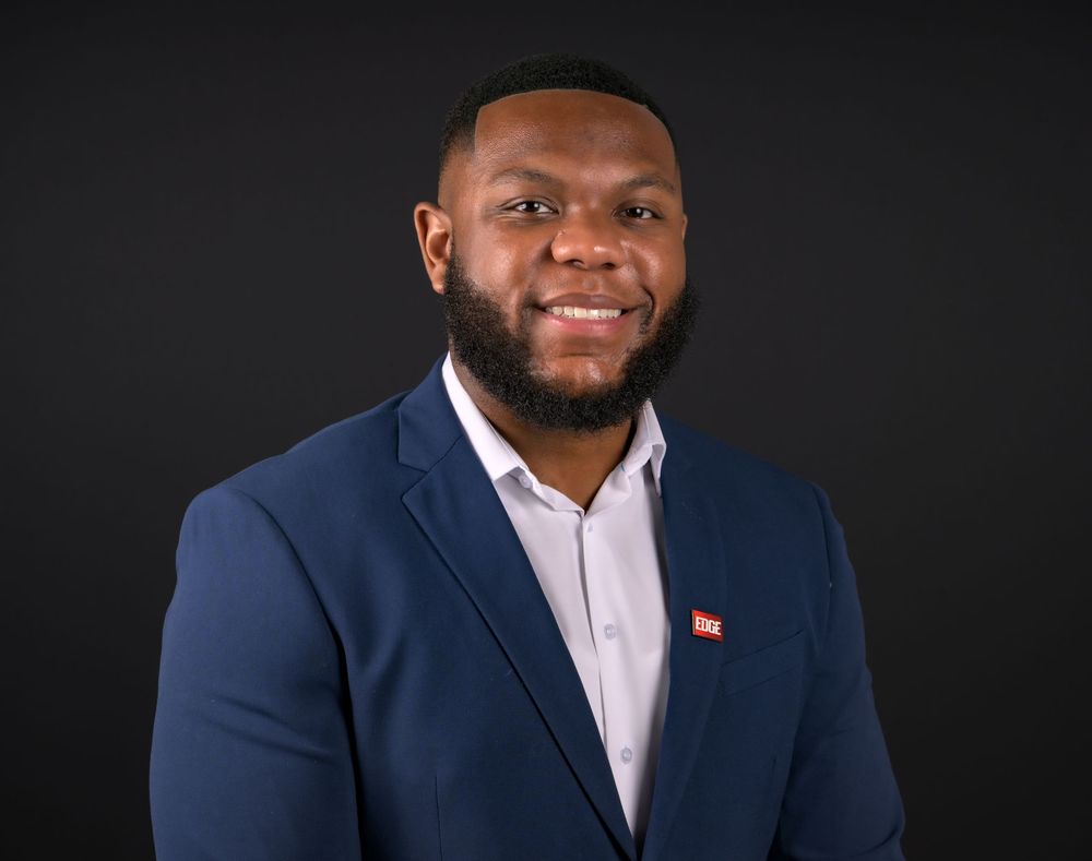 Professional headshots of business professionals in navy suits and light shirts against dark background.