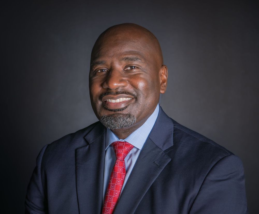 Professional headshot series showing a person in a navy suit and red tie against a dark gray background.