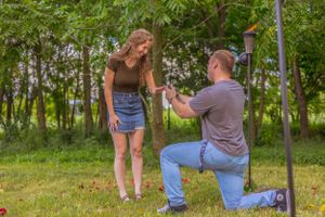 Romantic outdoor engagement photoshoot in wooded park setting at sunset.
