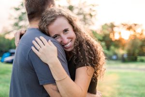 Couple embracing during sunset engagement photo session in park.