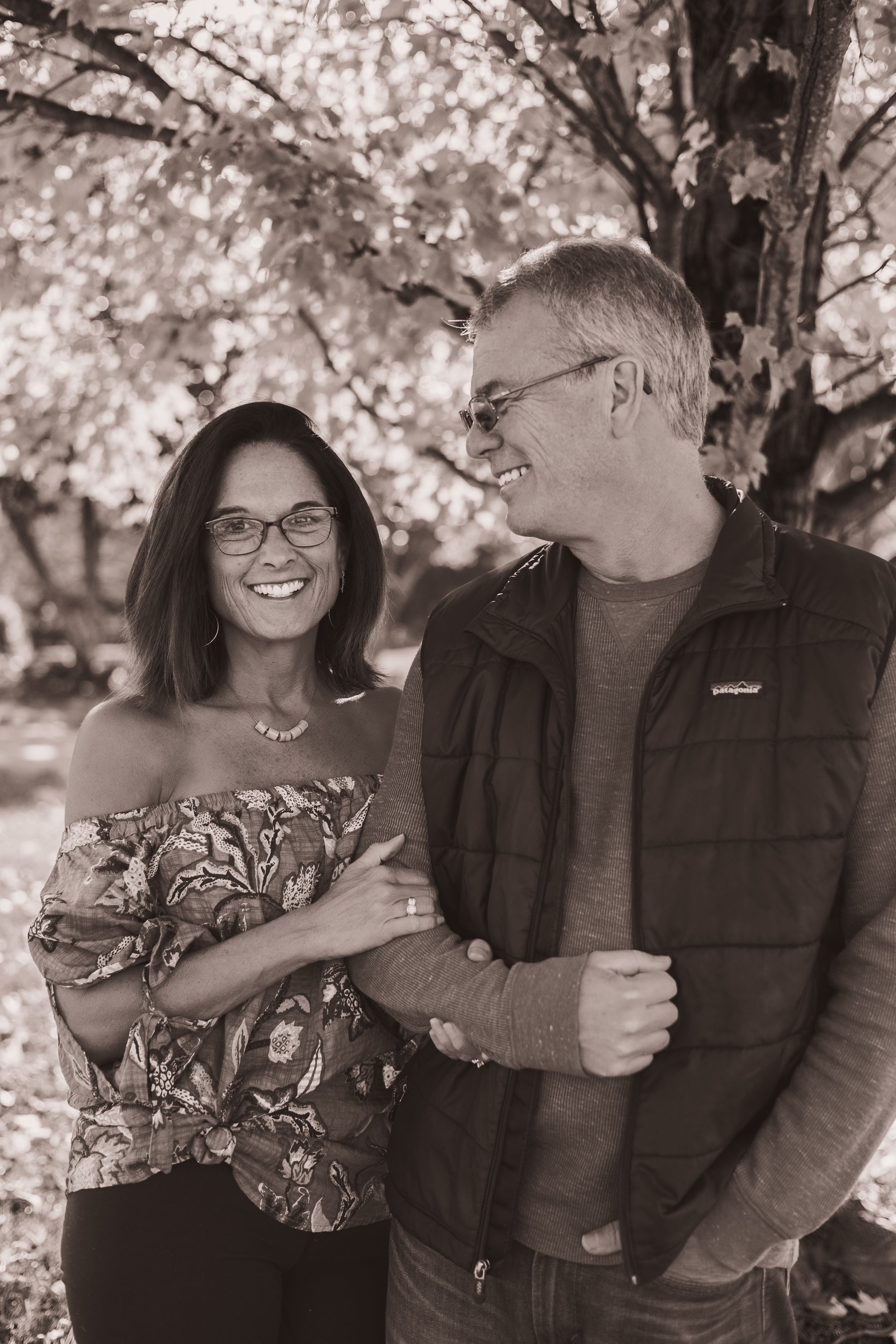 Black and white portrait of couple beneath blooming cherry blossom trees.
