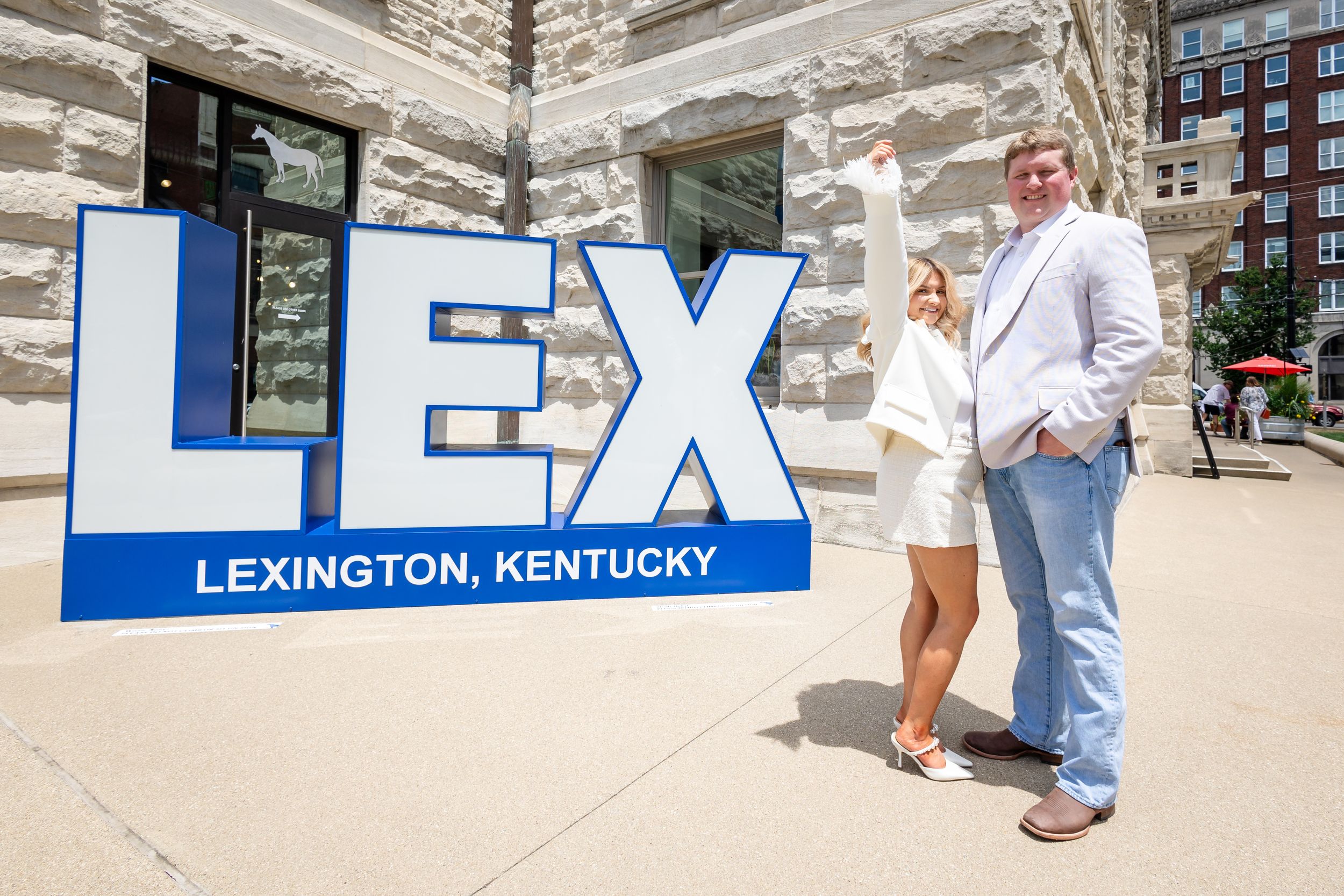 Couple posing with large LEX sign in downtown Lexington, Kentucky.