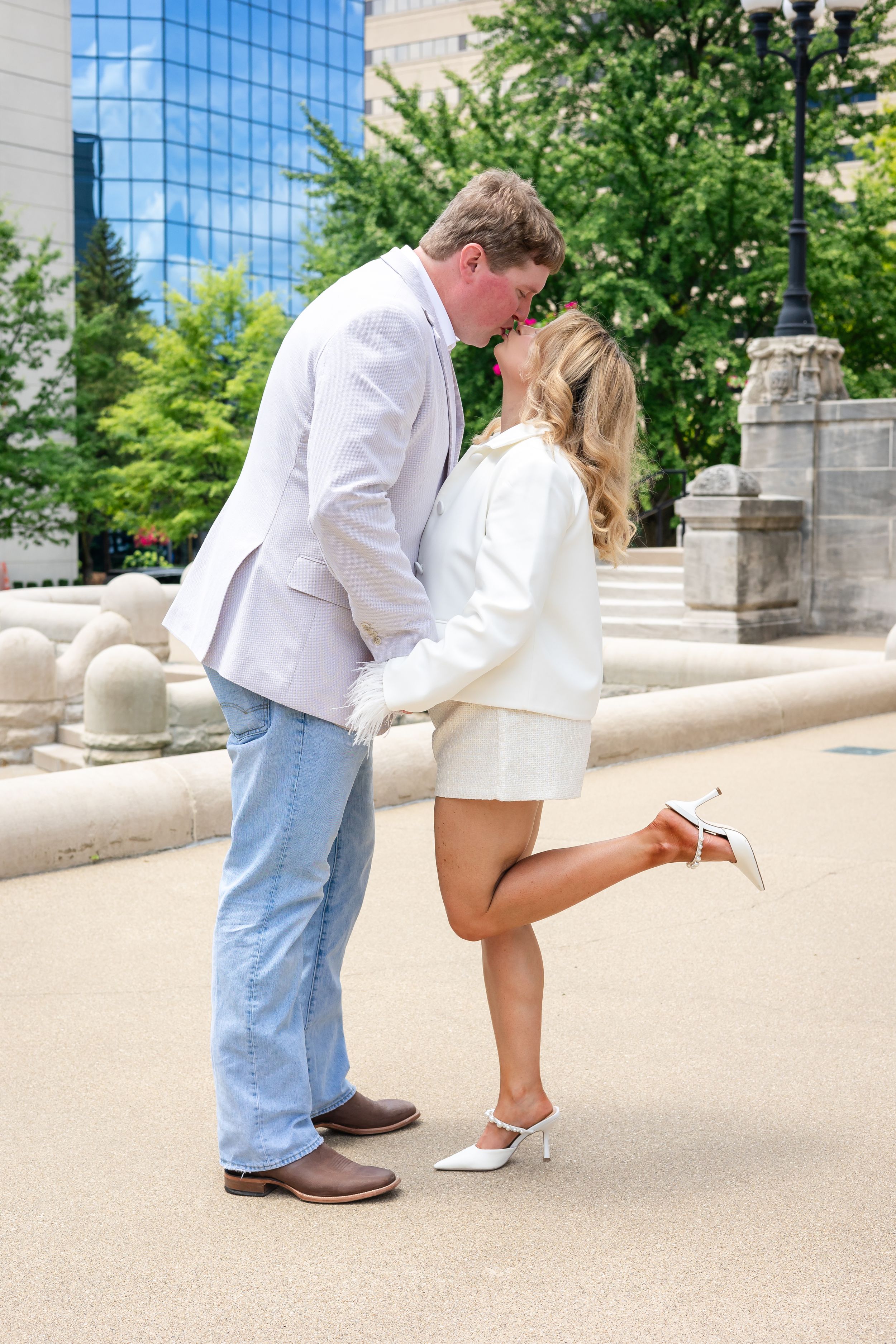 Romantic moment captured in front of modern glass building.