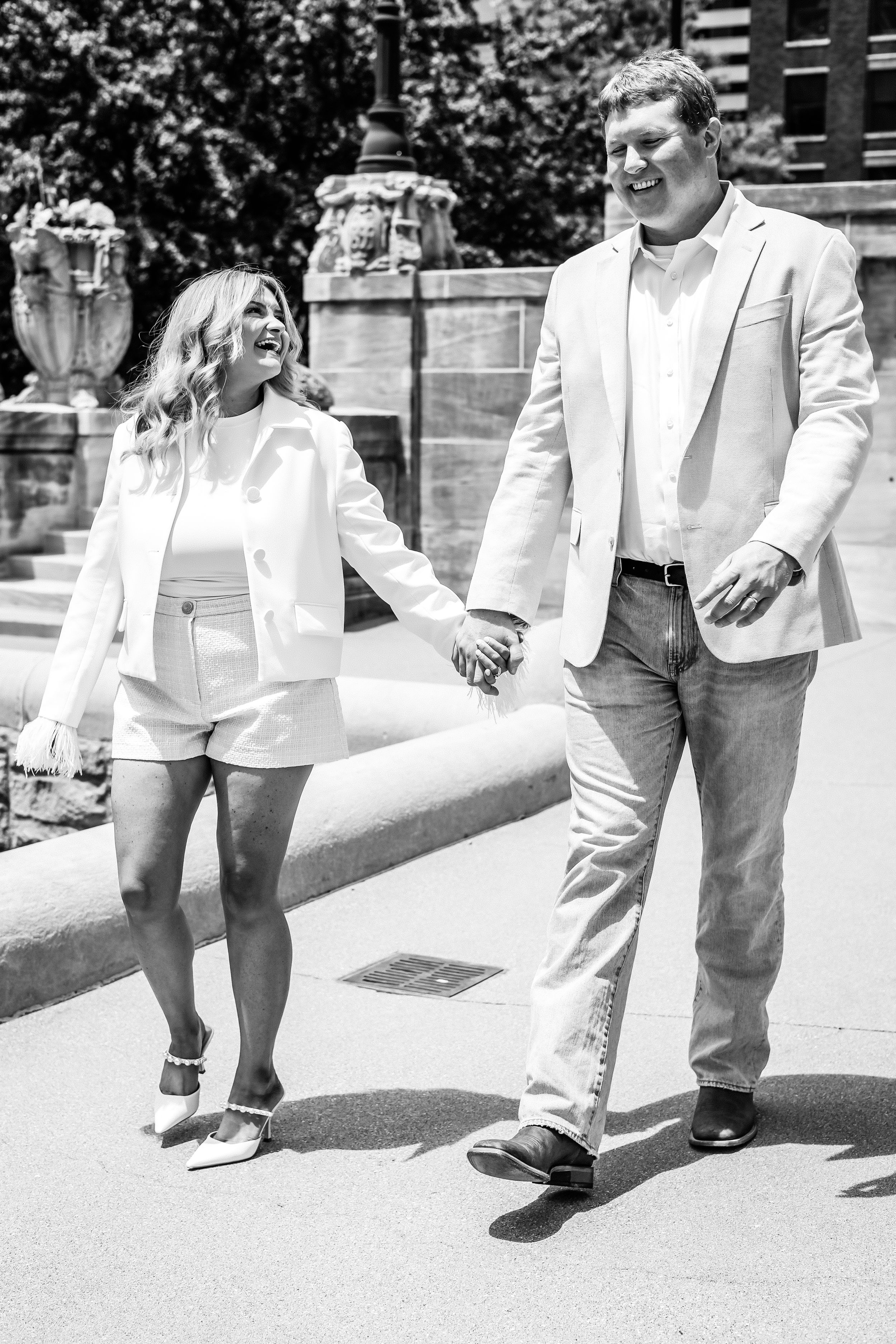 Romantic black and white photo of couple walking together in summer attire.