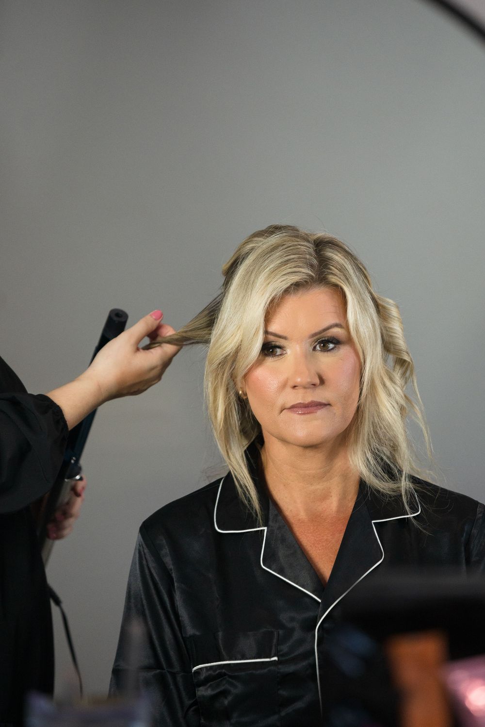 Series of photos showing makeup and hair styling being done on someone wearing a black robe with white trim.