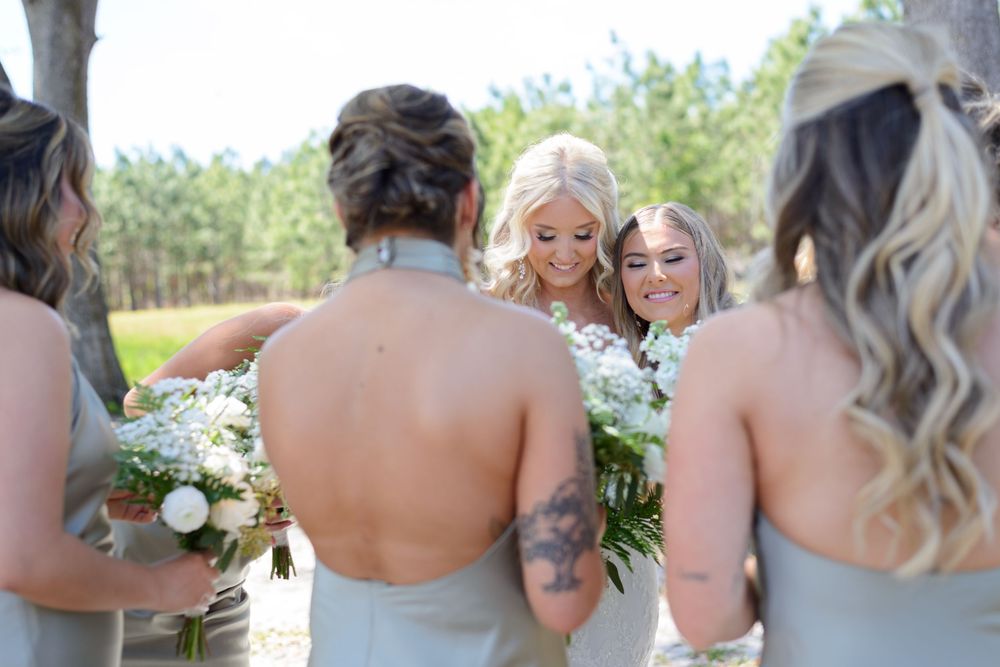 A wedding party laughs and smiles together during an outdoor photo session against a natural backdrop. little red wagon farms