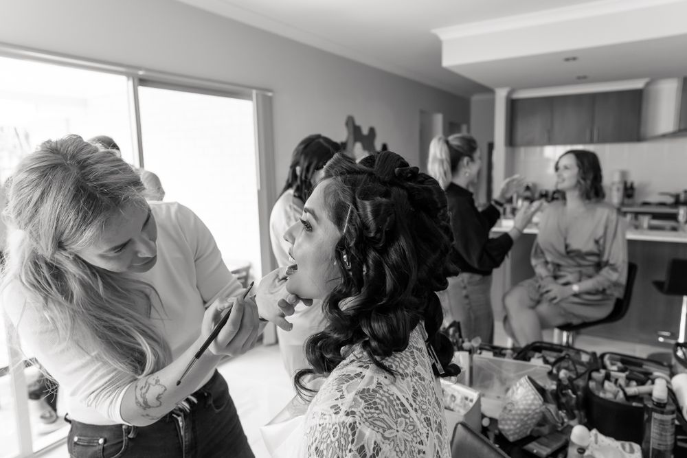 Black and white candid shot of wedding preparation with hair styling in progress.