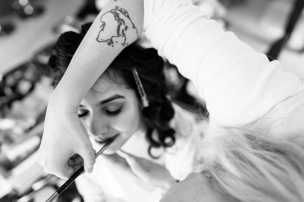 Monochrome image of bridal beauty preparation with makeup being applied.
