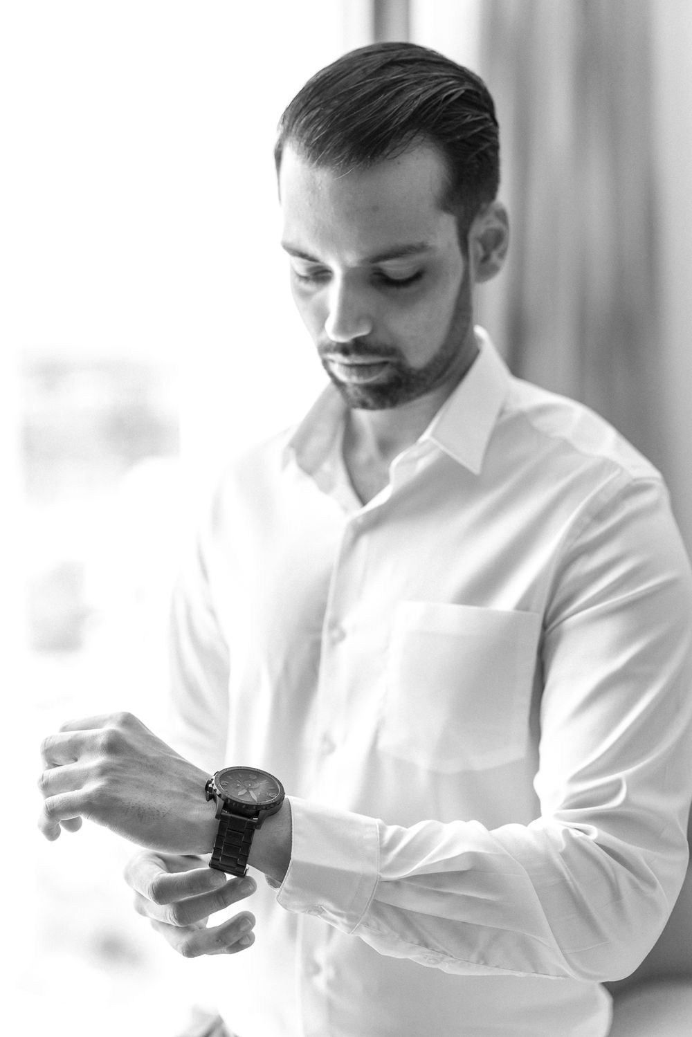 Black and white portrait of a person in a white dress shirt checking their watch.