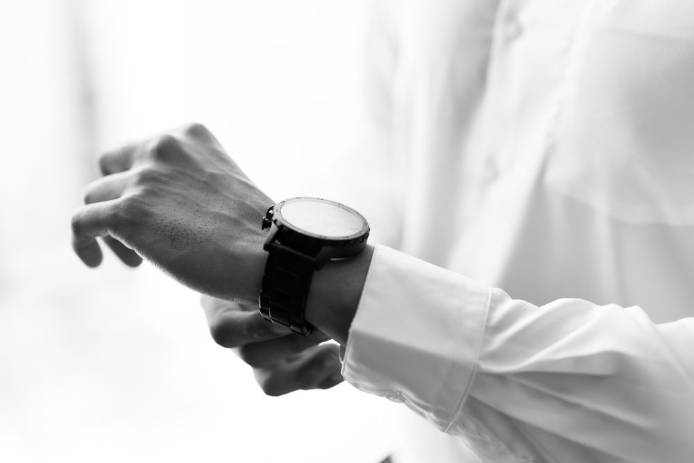 Black and white image of someone in formal attire putting on dress shoes.