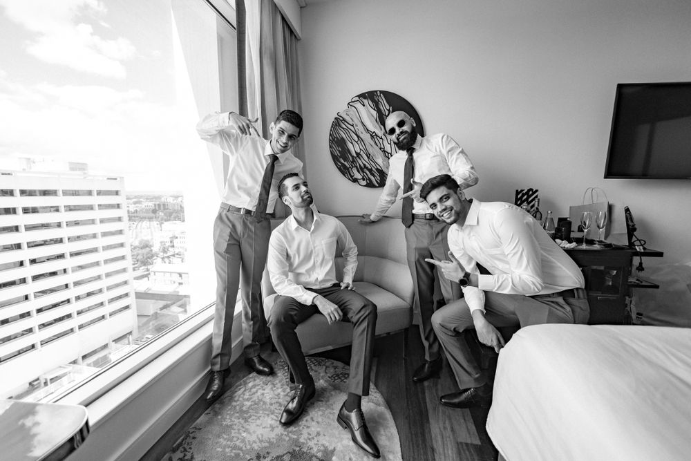 Candid photo of groomsmen sharing a humorous moment in a bright hotel room.