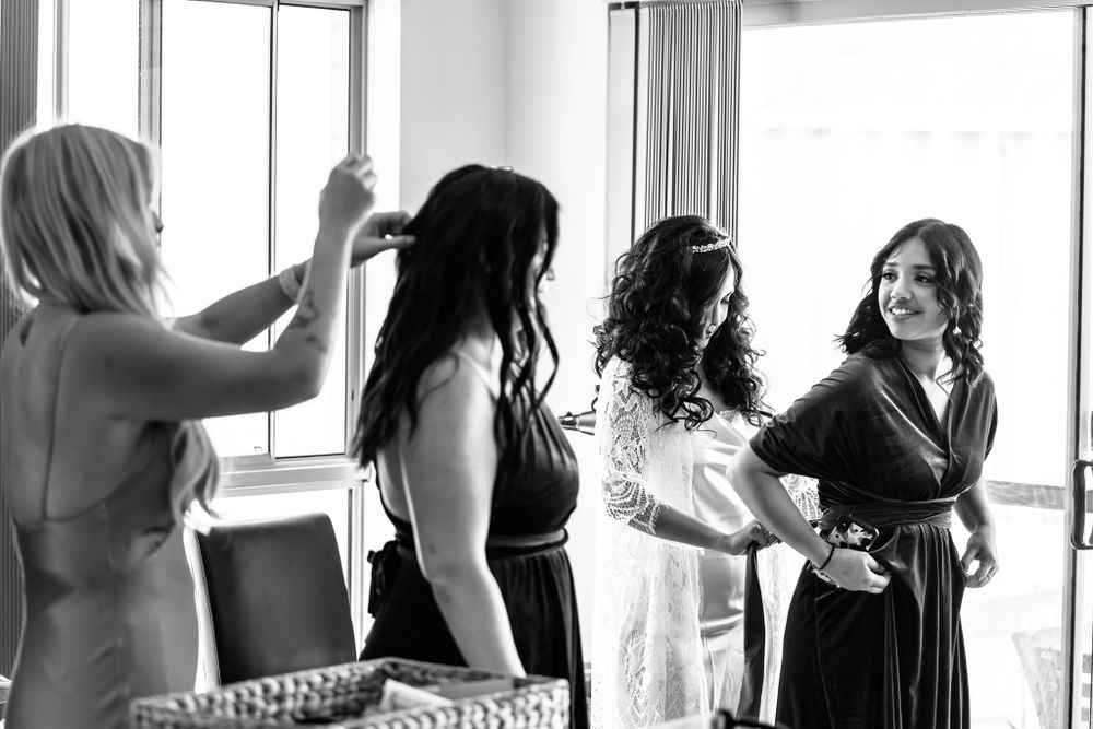 Black and white photo showing a wedding dress being prepared in a doorway.