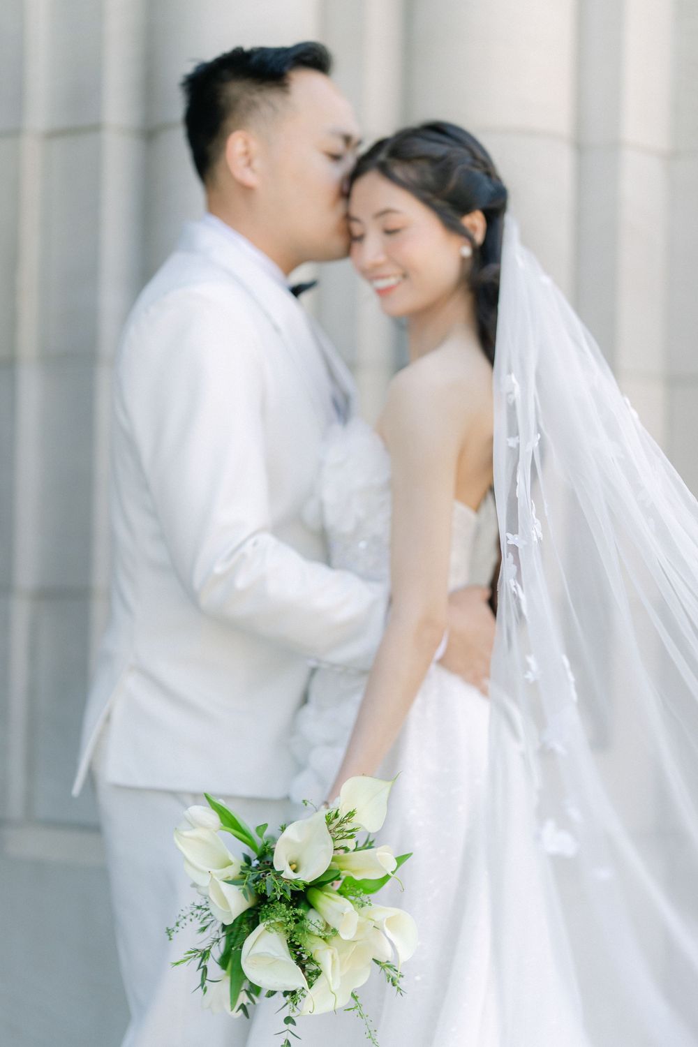 bride and groom standing together with a white floral bouquet during a classic wedding portrait