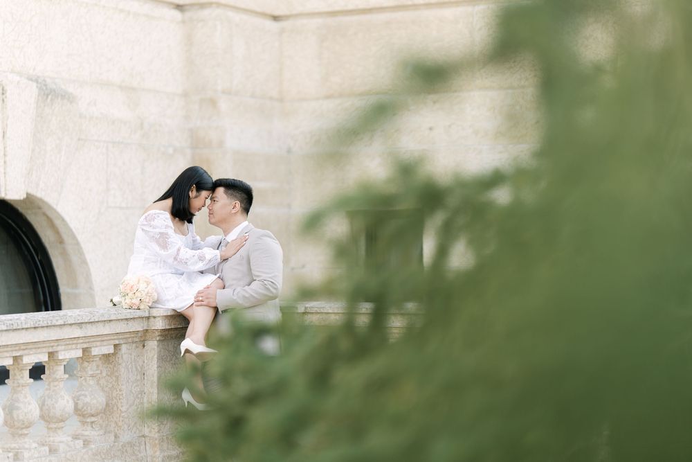 bride and groom sharing an intimate moment on a stone balcony framed by greenery