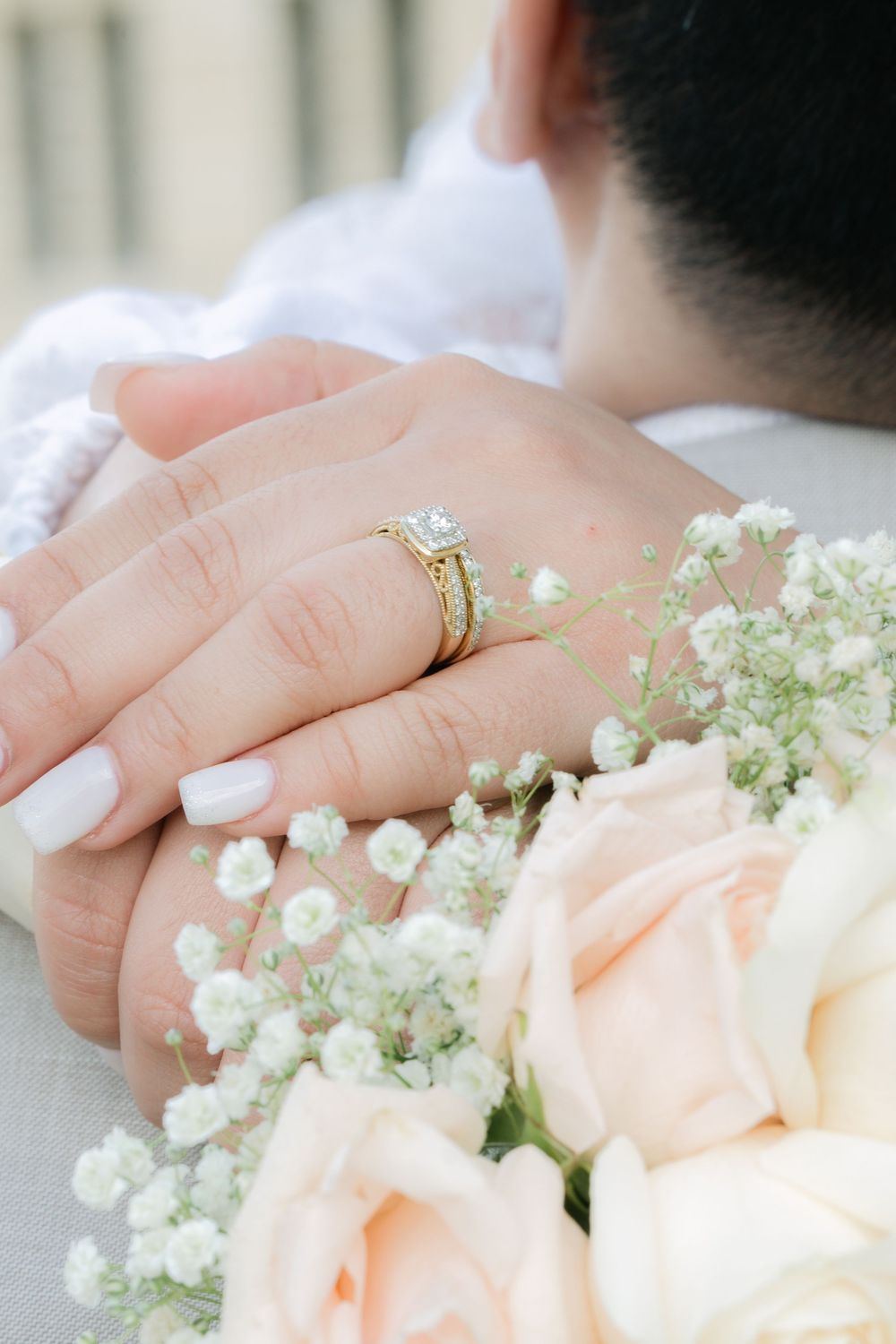 close-up of wedding rings on the bride's hand resting on a soft floral bouquet