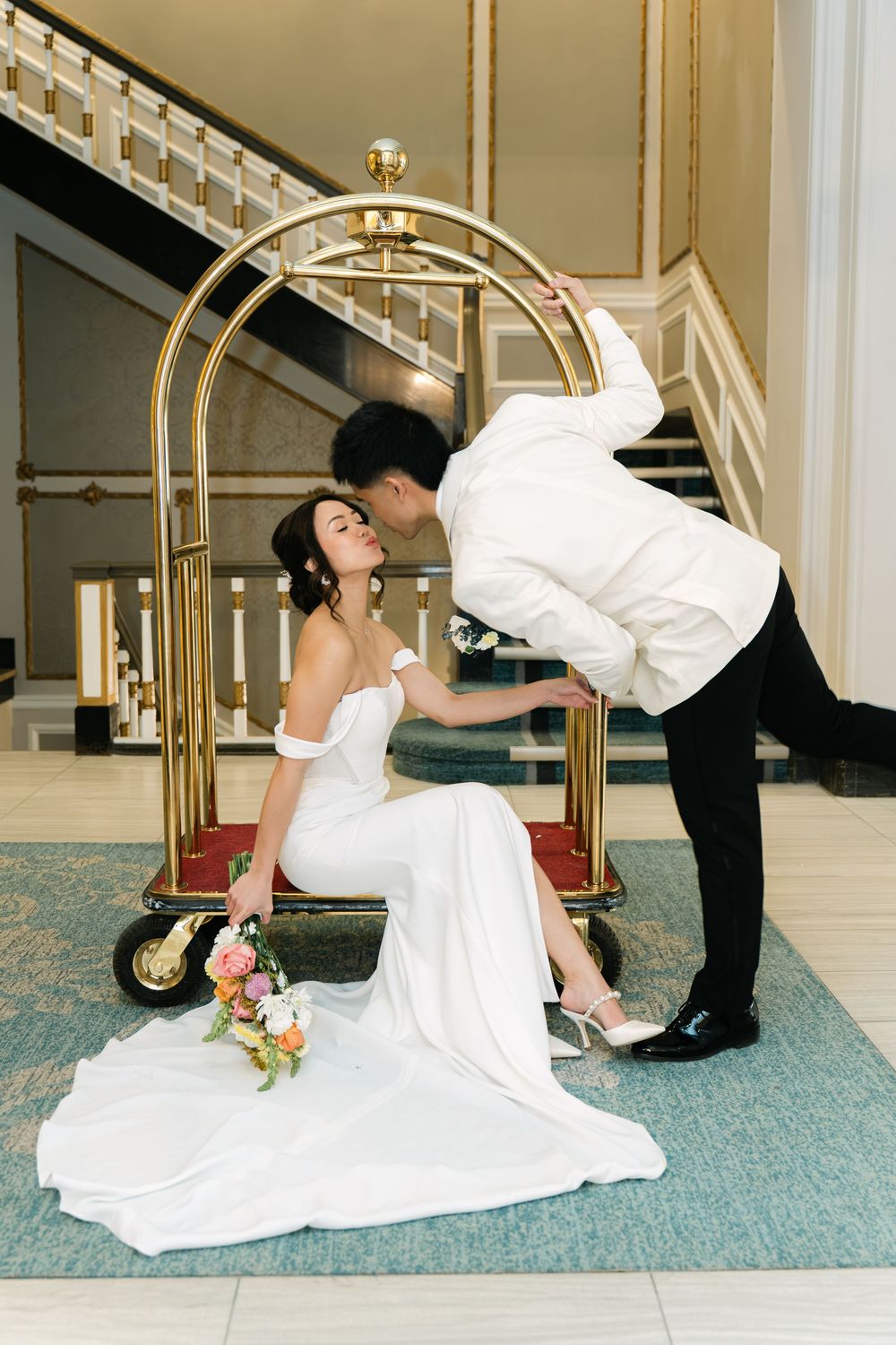 bride seated while groom stands beside her during an intimate wedding portraits indoors
