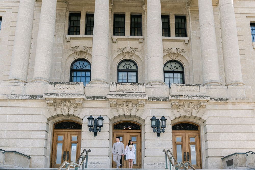 bride and groom standing on the steps of a historic building during an elegant wedding portrait