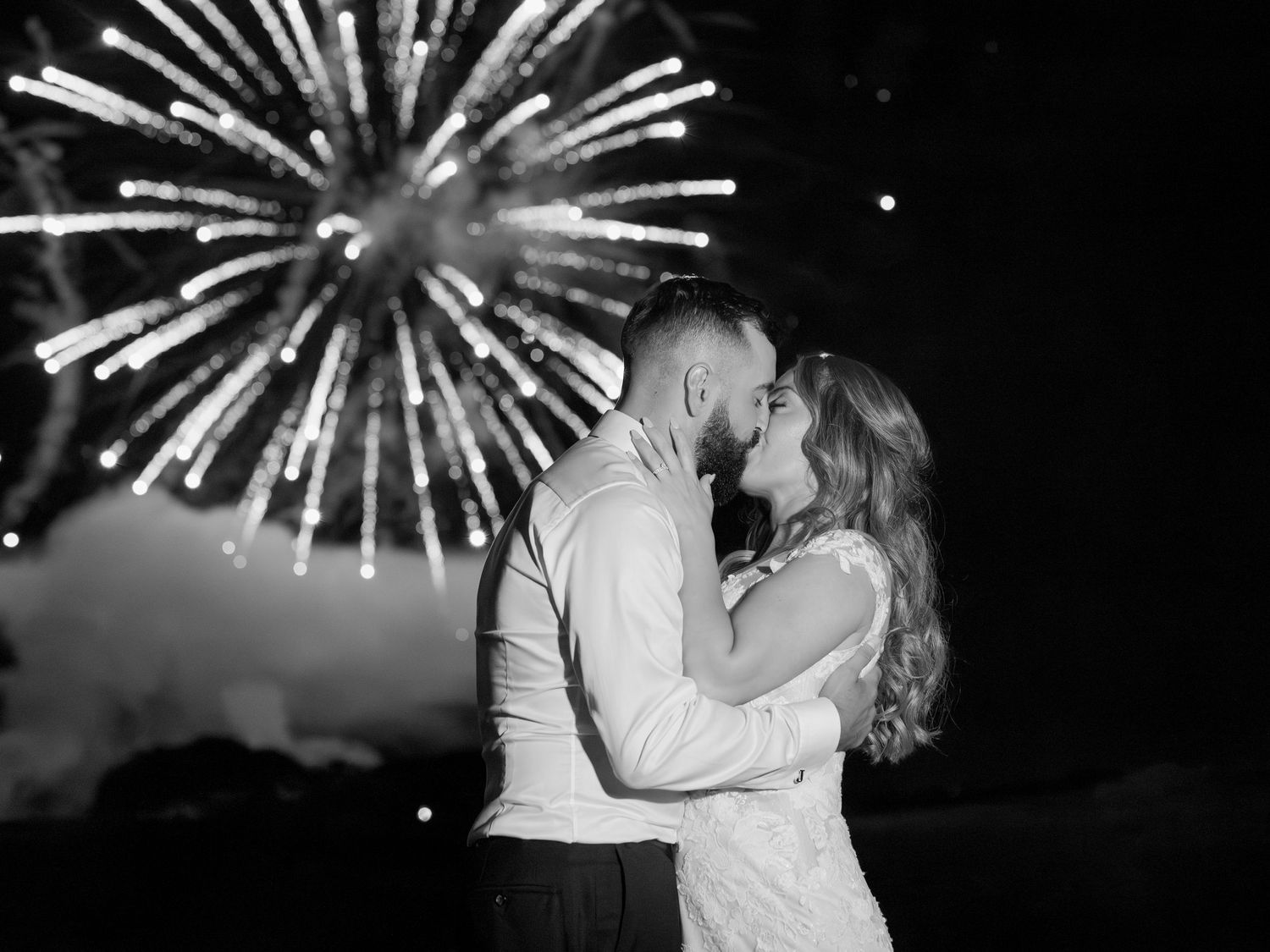 Couple dancing under sparkler lights during nighttime wedding celebration.