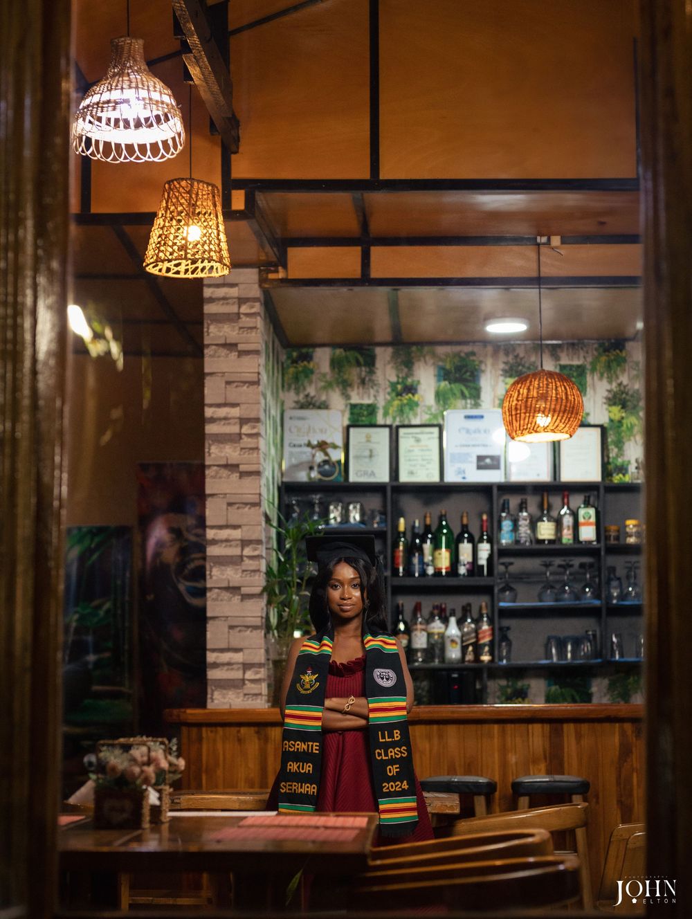 Interior view of a cozy bar with warm lighting, wooden accents, and bottles displayed on shelves behind the counter.