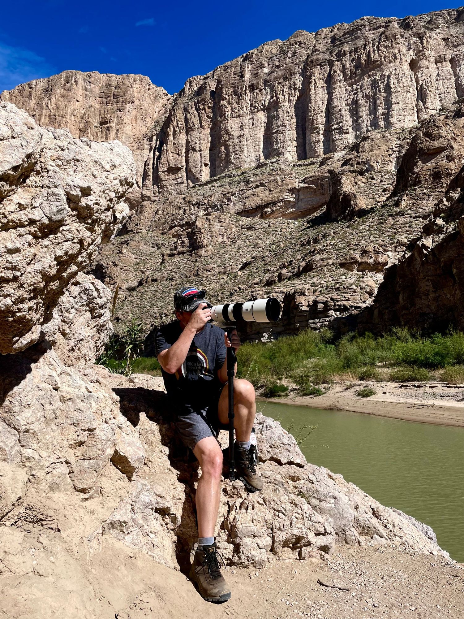 Photographer holding super telephoto lens in front of canyon wall