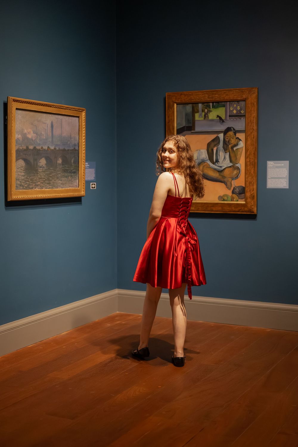 A sequence of photos showing someone in a red dress walking through an art gallery with blue walls and framed paintings.