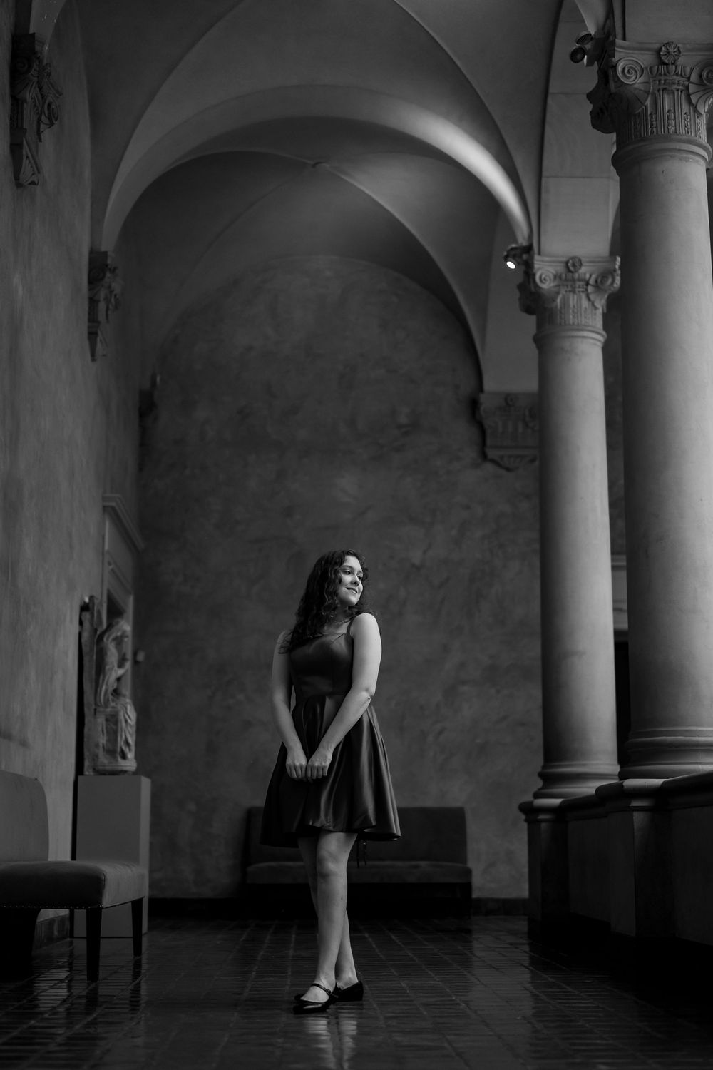 A black and white triptych shows a figure in a dress standing against pillars in a dark, atmospheric hallway.