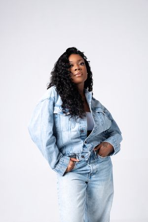 A model poses in an oversized light blue denim jacket and jeans ensemble against a white background in four poses.