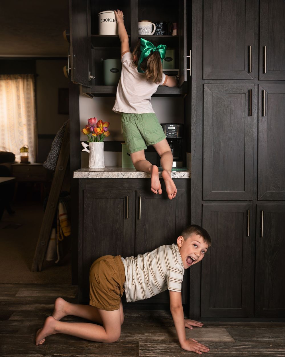 A sequence of photos showing a young child crawling and playing on a dark hardwood floor near black cabinets.