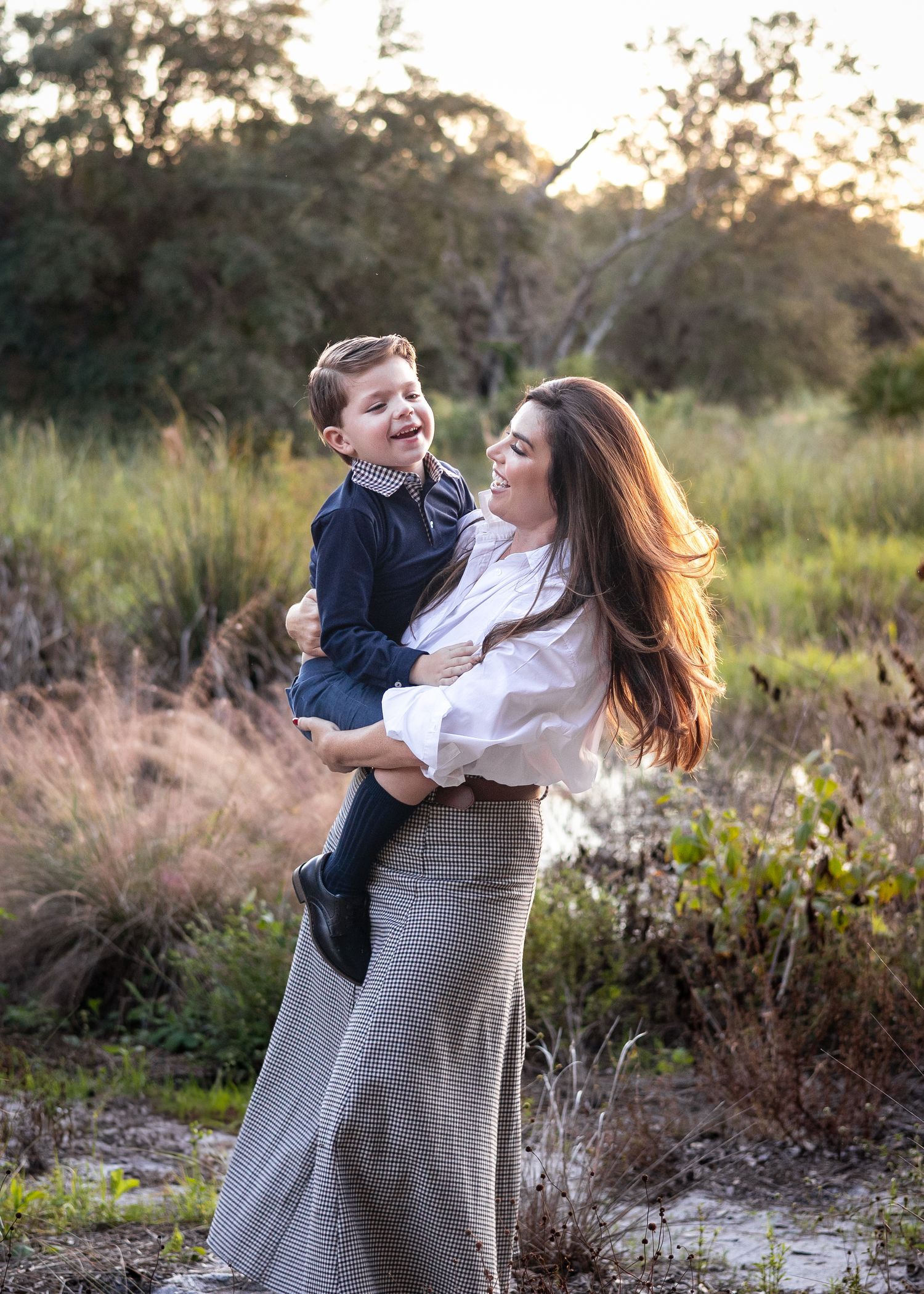 A joyful outdoor portrait at sunset with natural lighting and golden hour warmth in a field of tall grass.