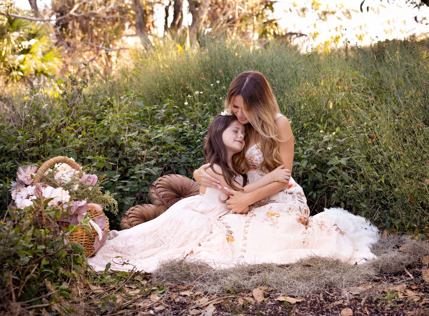 A mom in a flowing white dress reclines on autumn leaves during a Mother's Day outdoor mini session at sunset. Bohemian dresses.
