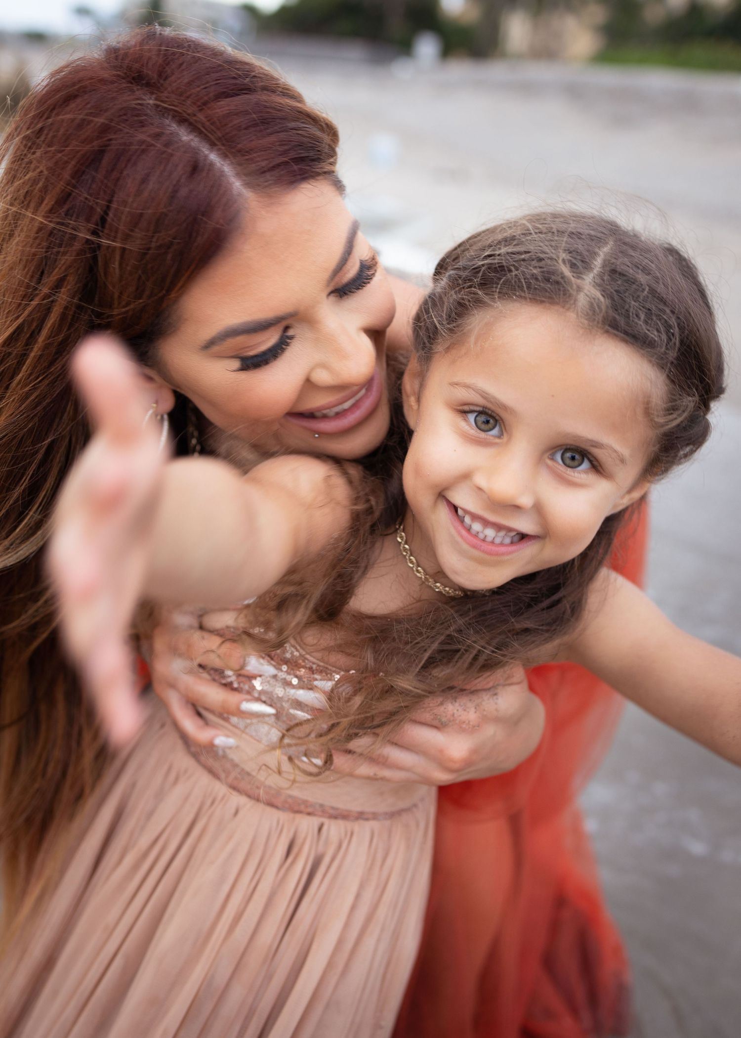 A heartwarming candid moment between a mom and daughter sharing laughter and affection outdoors. Bohemian Style Dresses.
