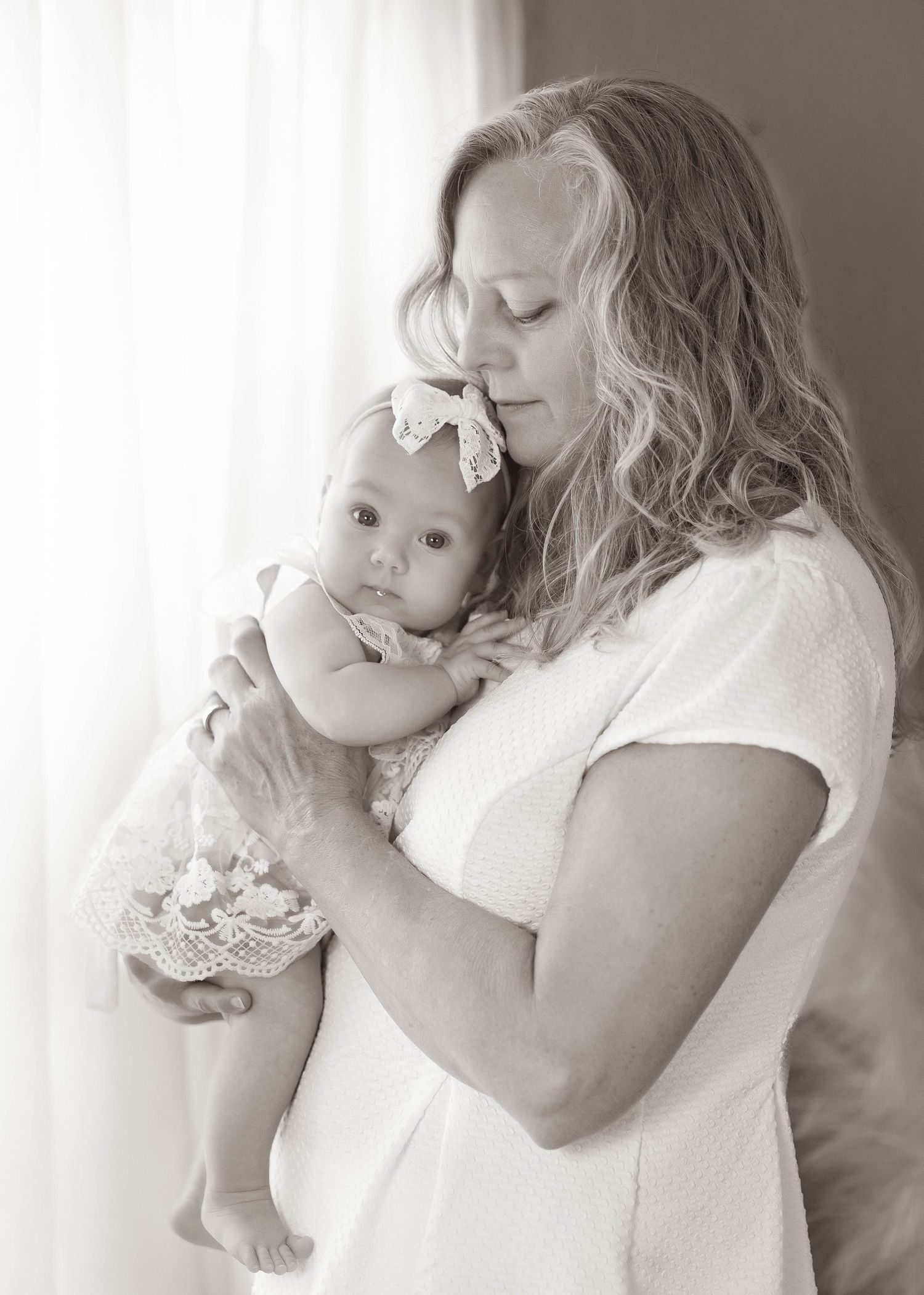 A tender black and white portrait series showing a mother and baby sharing intimate embraces and loving moments.