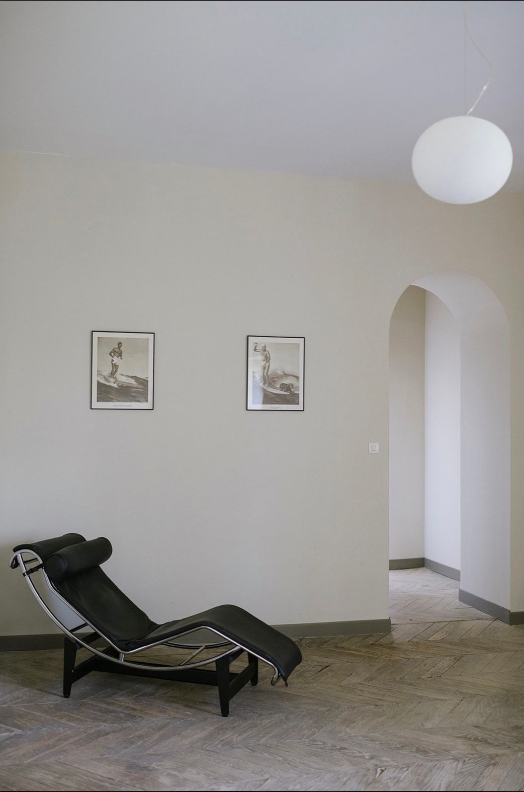 Minimalist gallery space with Le Corbusier chaise lounge chairs arranged against white walls and stone flooring.