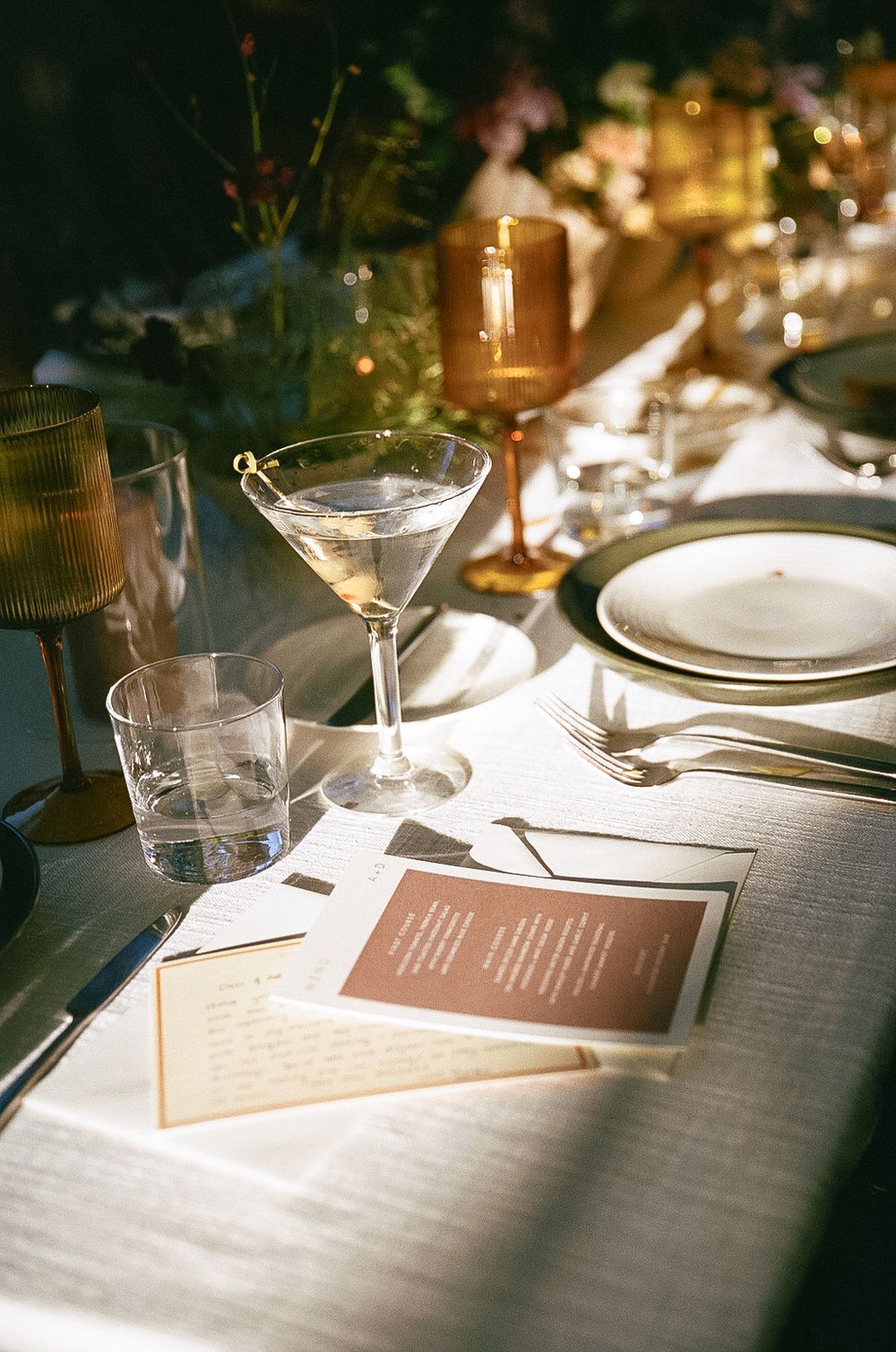 An elegant table setting with martini glass, menu cards and candlelight creating a romantic fine dining atmosphere.