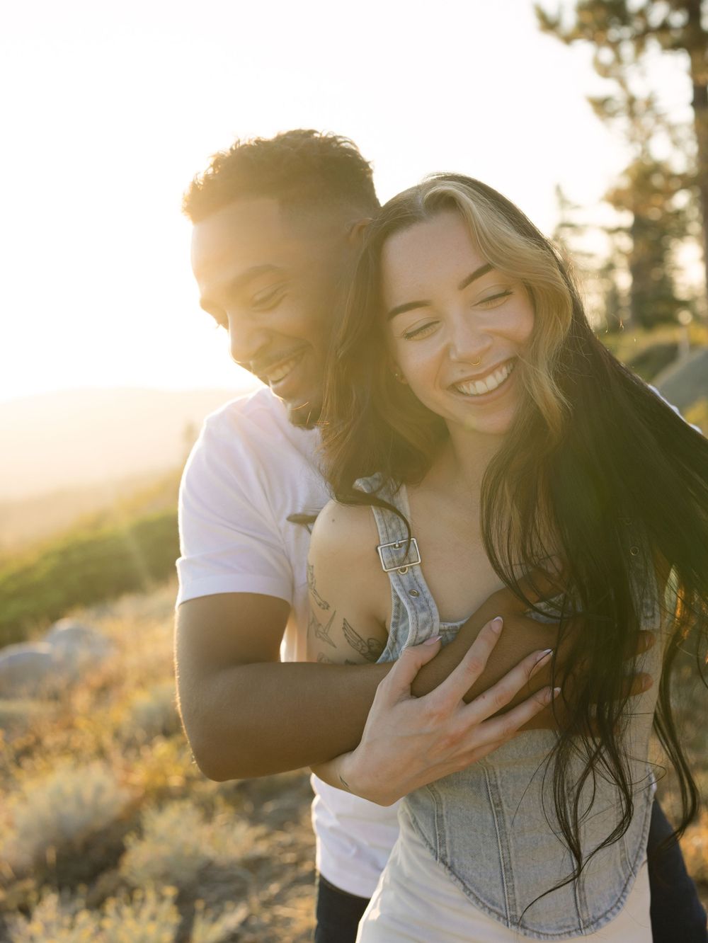 Joyful couple laughing together during sunset engagement photo session.